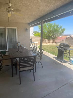 A shaded patio area with a dining table and grill.