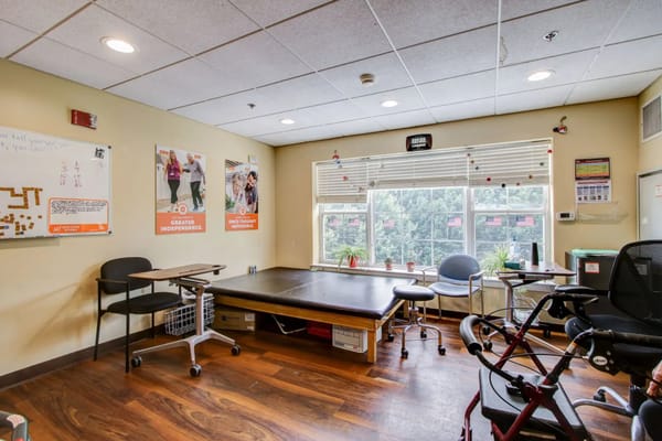 A therapy room featuring a treatment table, chairs, and motivational posters.