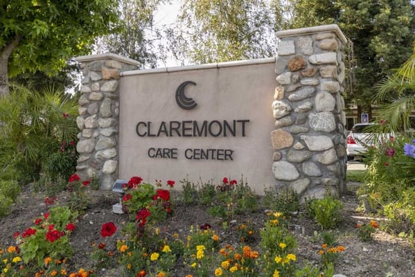 Stone sign for Claremont Care Center surrounded by flowers