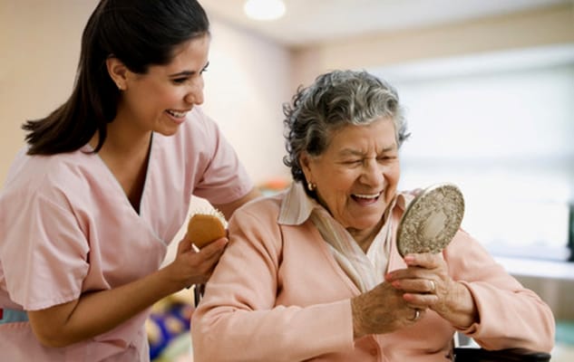 A caregiver assisting a senior woman with a mirror