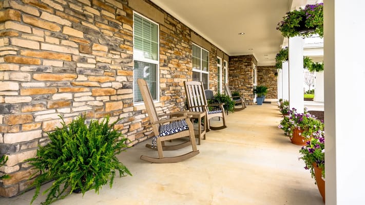 A peaceful porch featuring rocking chairs and flowering plants.