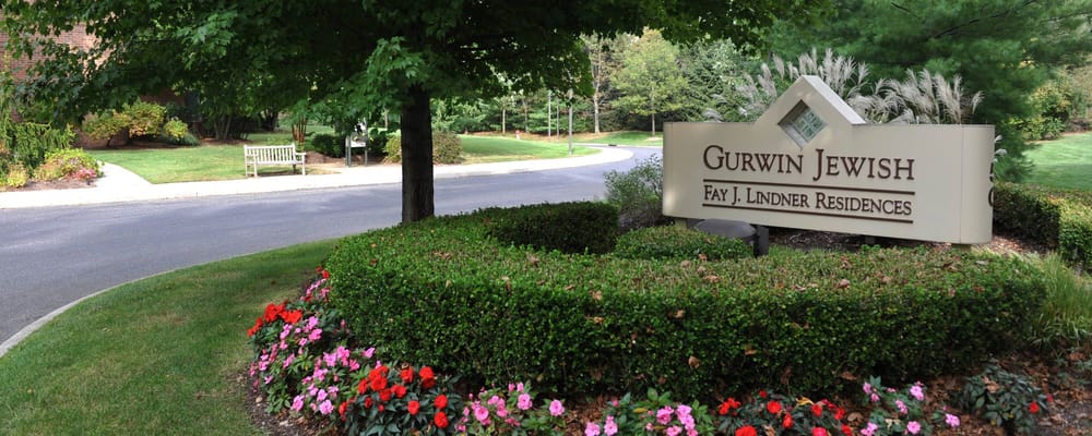 Sign of Gurwin Jewish - Fay J. Lindner Residences surrounded by flowers