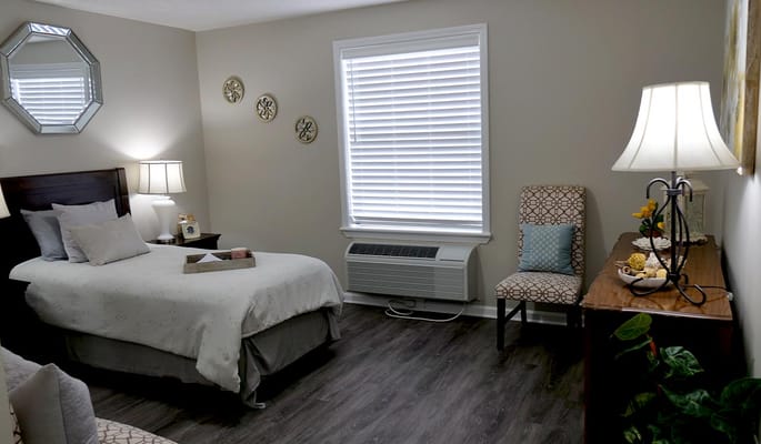 A well-furnished bedroom with a bed, lamp, and decorative chair.