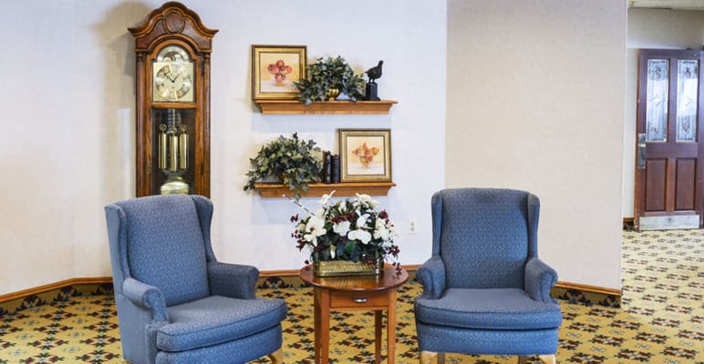 Two blue armchairs beside a small table and decorative items on the wall.