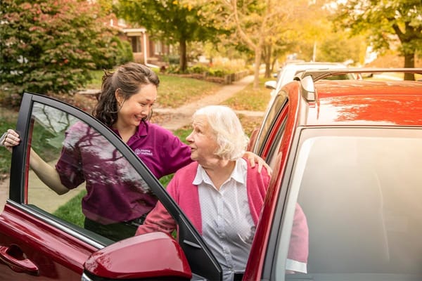 Caregiver assisting senior client into a car