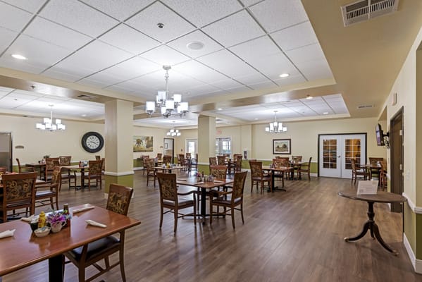 Bright dining room with tables and chairs set up for residents