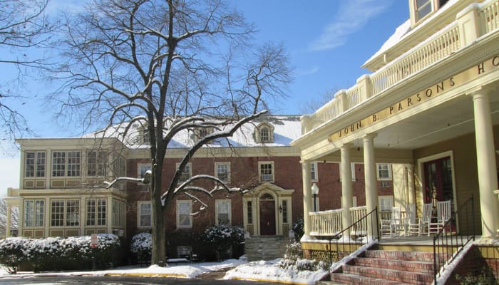 Exterior view of John B. Parsons Assisted Living Community with snow-covered ground and trees.