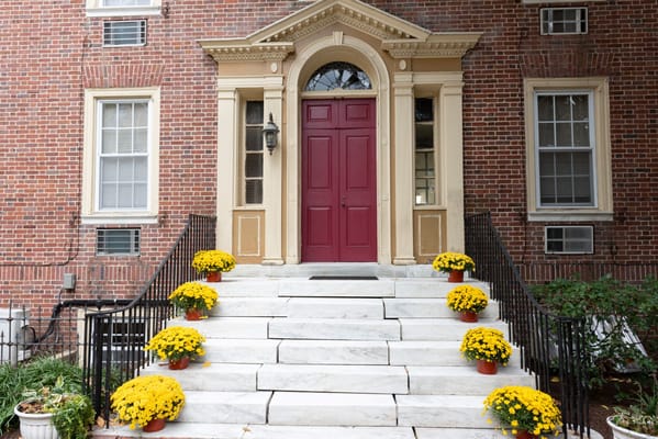Entrance with red door and yellow flower pots on stairs