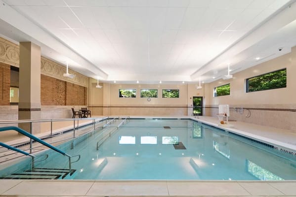 Indoor swimming pool with windows and seating area