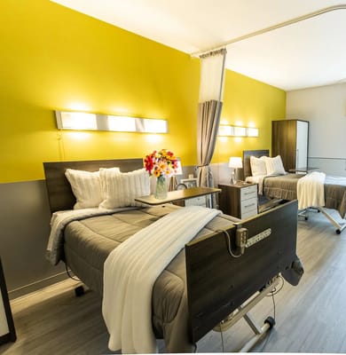 Brightly lit bedroom with two hospital beds and a vase of flowers