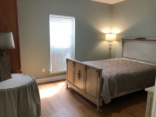 Brightly lit bedroom with a bed, lamp, and side table