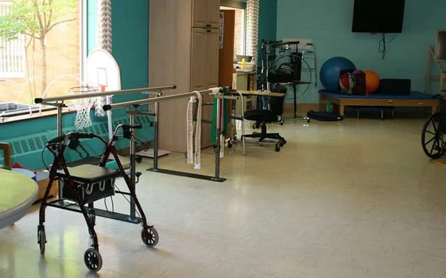 An accessible therapy room with equipment including a walker and exercise tools.