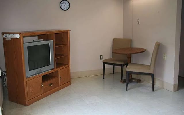 A living room with a TV and a small dining table and chairs