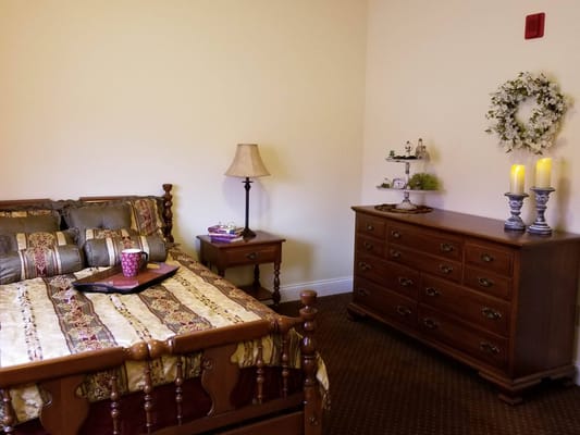 A cozy resident room with a bed and dresser