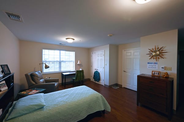 Bright bedroom with a bed, armchair, and desk.