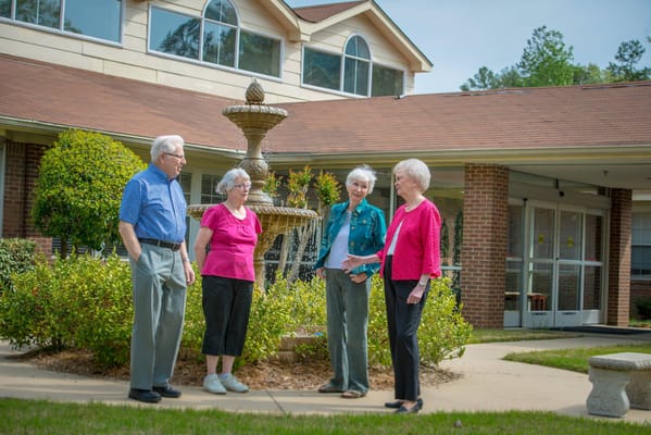 Four senior residents gathered by a fountain at Parkway Village.