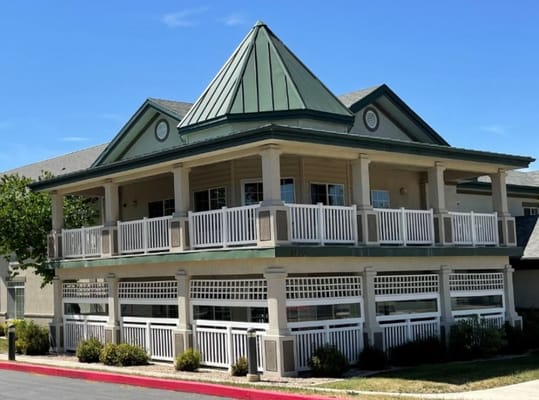 Front view of PeachTree Place Assisted Living facility with a green roof and white railings.