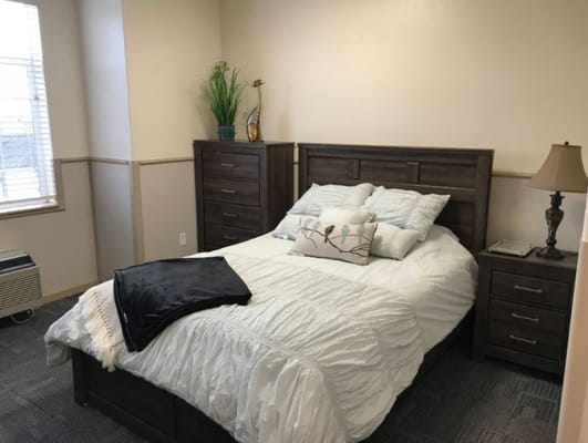 A well-furnished bedroom with a double bed, dresser, and lamp.