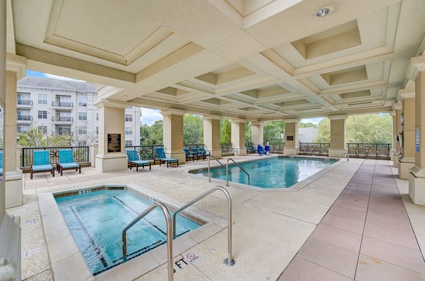 Indoor swimming pool area with two pools and lounge chairs