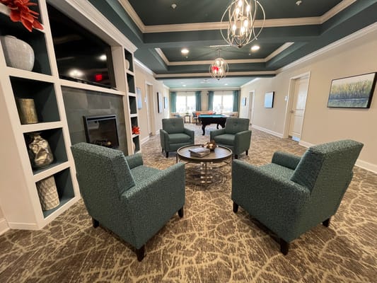 Cozy lounge with teal chairs and a coffee table in Avalon Assisted Living