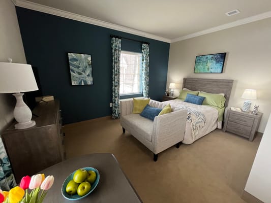 A cozy bedroom featuring a bed, decorative pillows, and a stylish armchair.
