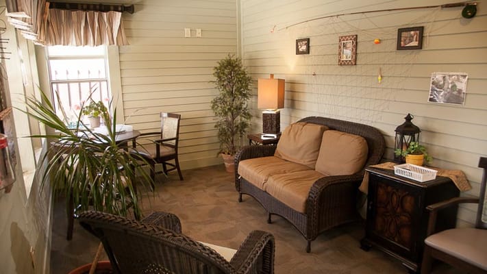 A comfortable seating area with a couch, chair, and indoor plants.