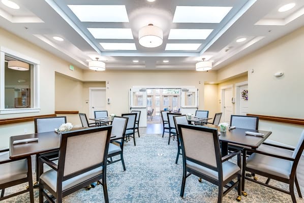 Dining area with tables and chairs in River Terrace Memory Care