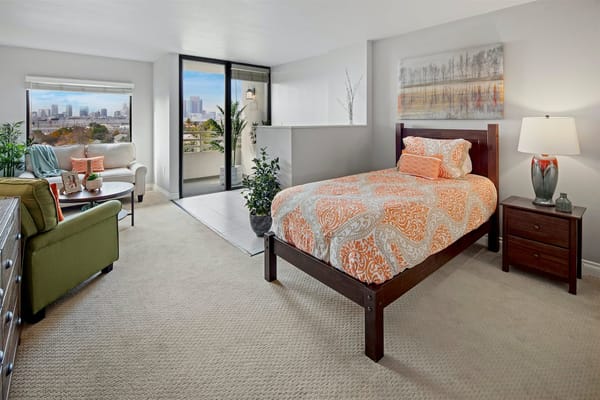 Cozy bedroom with a view in Sakura Gardens senior living facility.