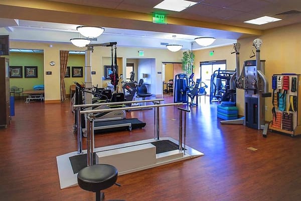 Interior view of a therapy room equipped with exercise machines and rehabilitation equipment.