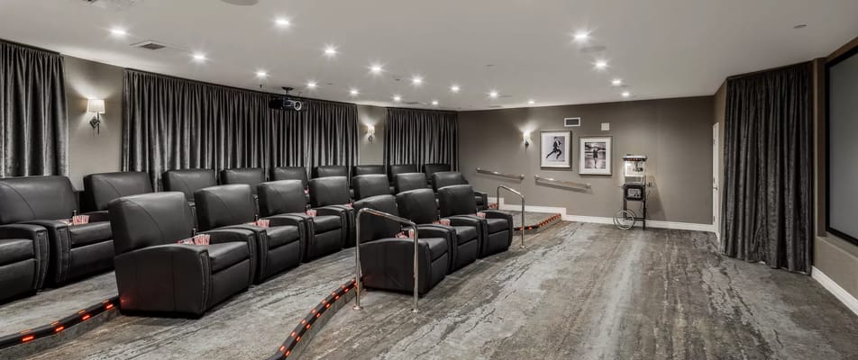 Cozy theater room with black reclining seats and movie screen