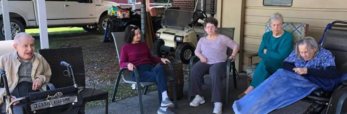 Five seniors sitting outside, engaged in conversation on a sunny day.