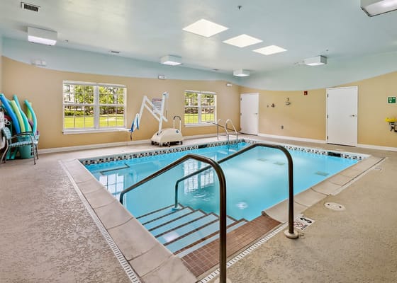Indoor swimming pool with accessible lift and colorful pool noodles.