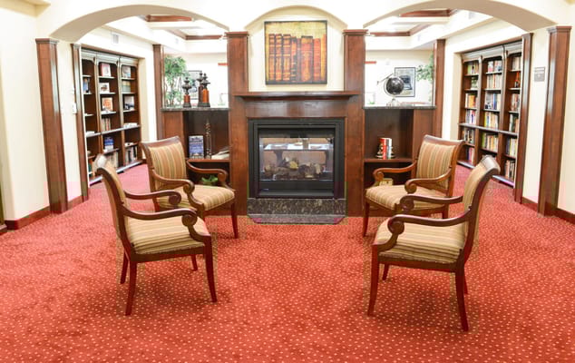 Lounge with striped chairs and a fireplace at Stoneridge Gracious Retirement Living.