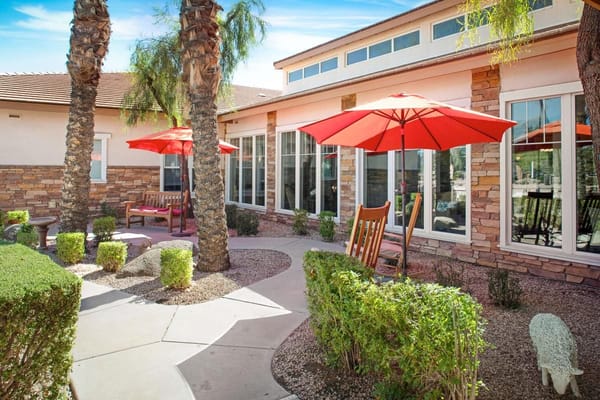 Patio area with red umbrellas and rocking chairs at Sunrise of Chandler