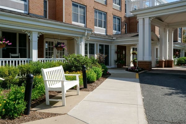 White bench in a landscaped entrance area of Sunrise of Upper St. Clair