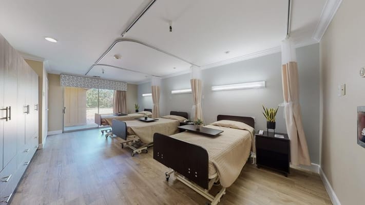 Two adjustable beds in a bright, spacious room with a sliding door and outdoor view.