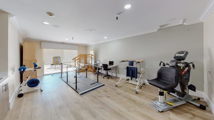 Interior of a therapy room with exercise equipment and workstations