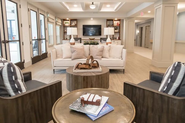 A cozy living room with a sofa, armchairs, wooden coffee table, and lamps.