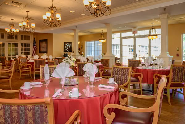 Elegant dining room set for a meal with red tablecloths and flowers
