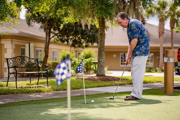 A senior man playing mini golf in a courtyard.