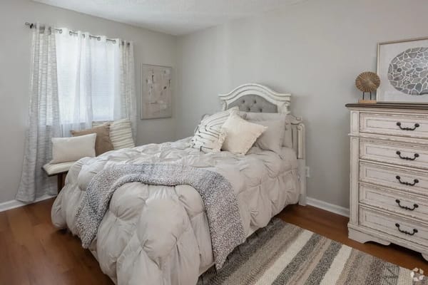 A serene bedroom with a bed, decorative pillows, and natural light.