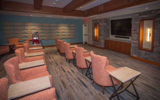 Cozy lounge area with orange upholstered chairs and a large TV
