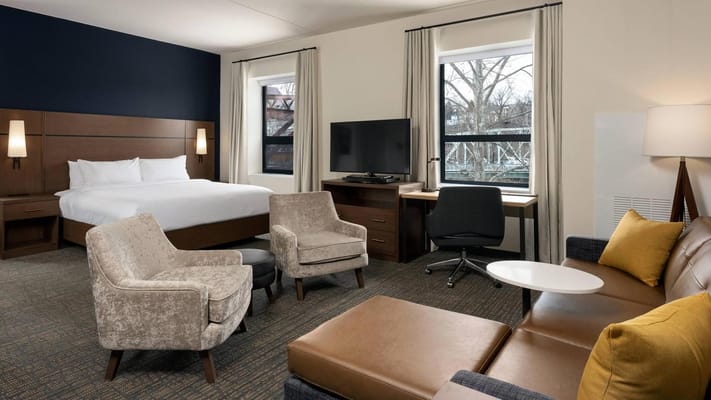 Contemporary bedroom with bed, seating area, and workspace.