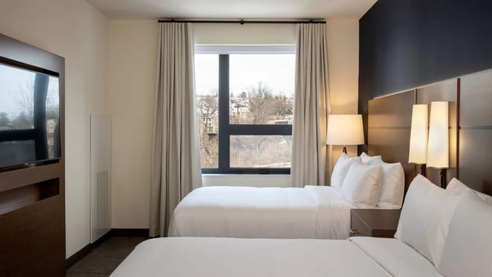 Bright guest bedroom with two beds, large window, and modern decor.