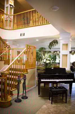 Bright interior of a common area with a piano and sculptures