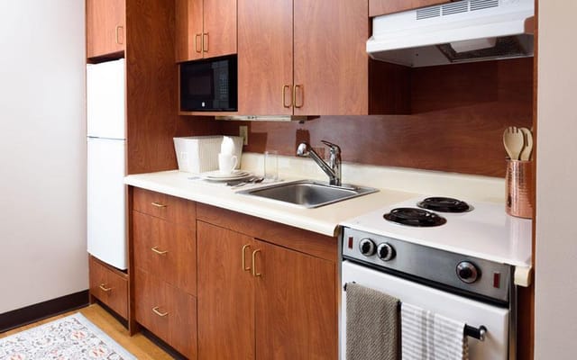 A compact kitchen setup with wooden cabinets, stove, and sink.