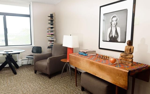 A cozy living room area featuring a chair, table, lamp, and decorative items.