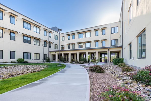 Pathway through the courtyard of The Watermark at Cherry Hills with flower beds.