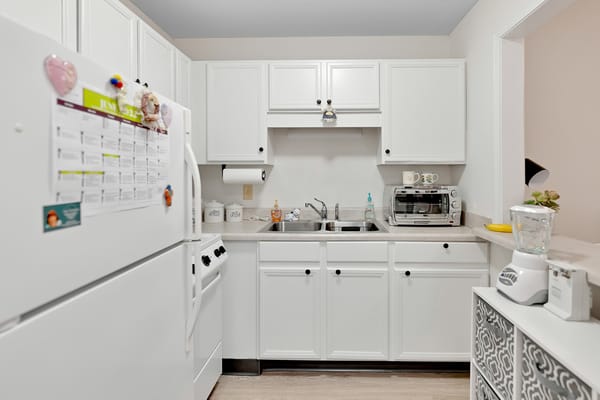 A bright kitchen with white cabinetry and appliances.
