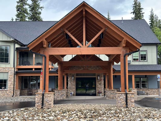 Front entrance of Timber Creek Senior Living showing wooden beams and stone facade